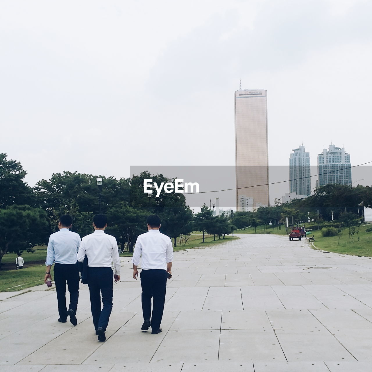 REAR VIEW OF MEN WALKING ON FOOTPATH IN PARK