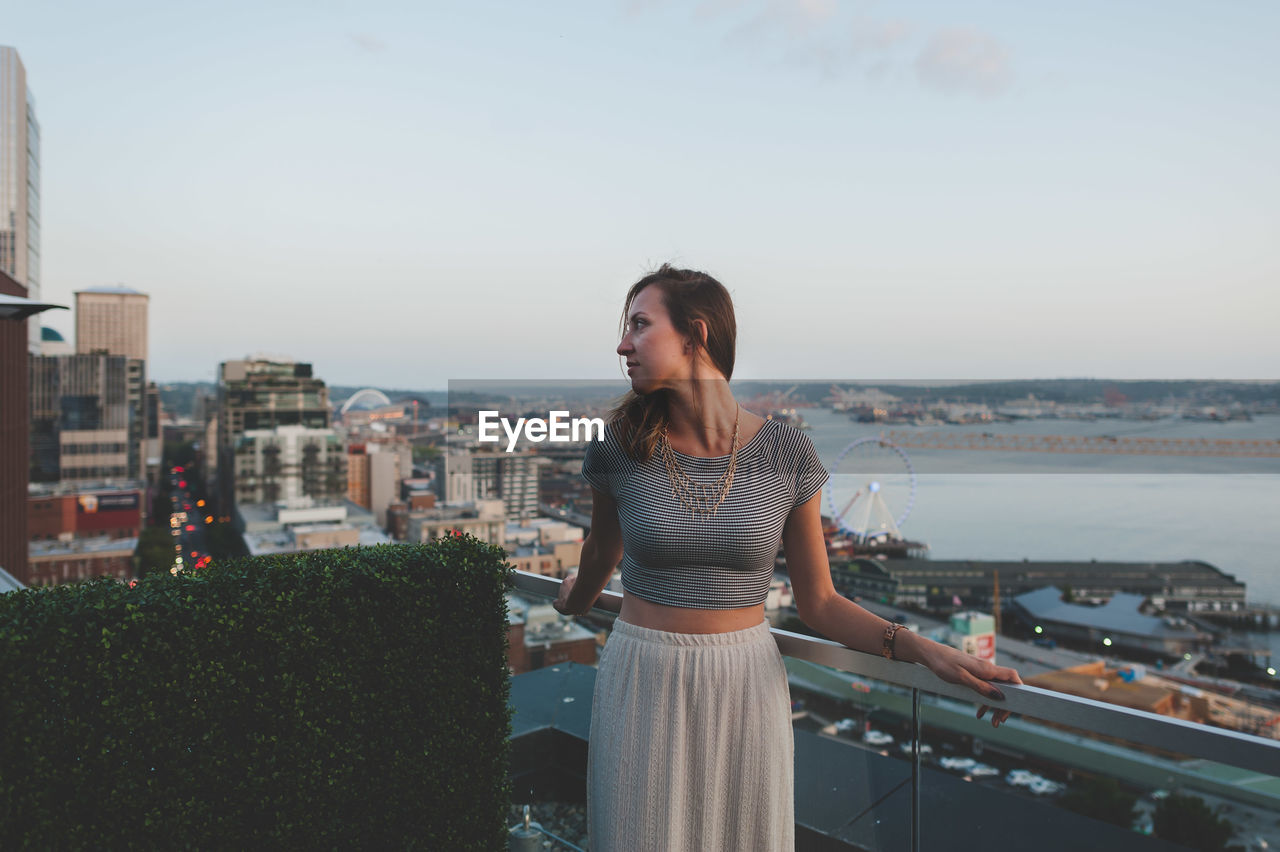 Woman standing by railing against sky