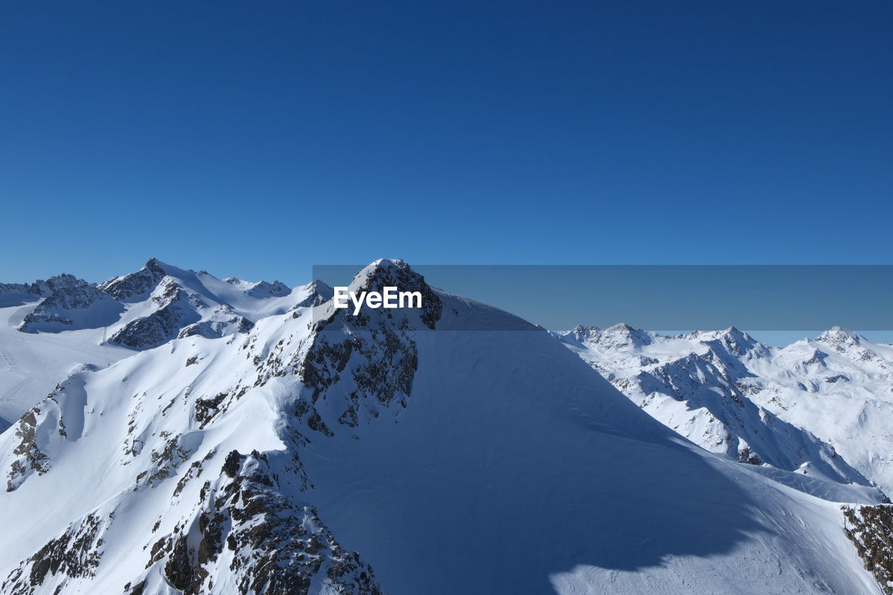 Scenic view of snowcapped mountains against clear blue sky