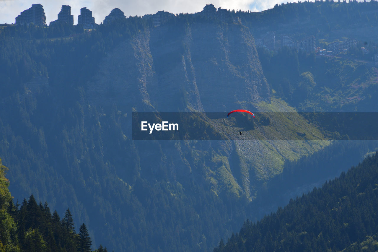 PEOPLE PARAGLIDING AGAINST MOUNTAIN