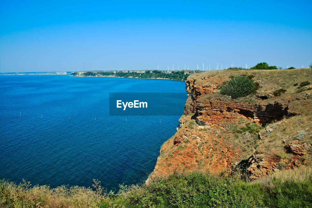 High angle view of cliff and sea against clear sky