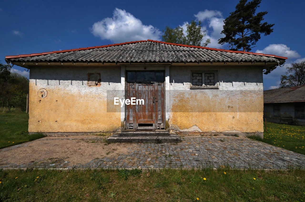 Exterior of old house on field against sky