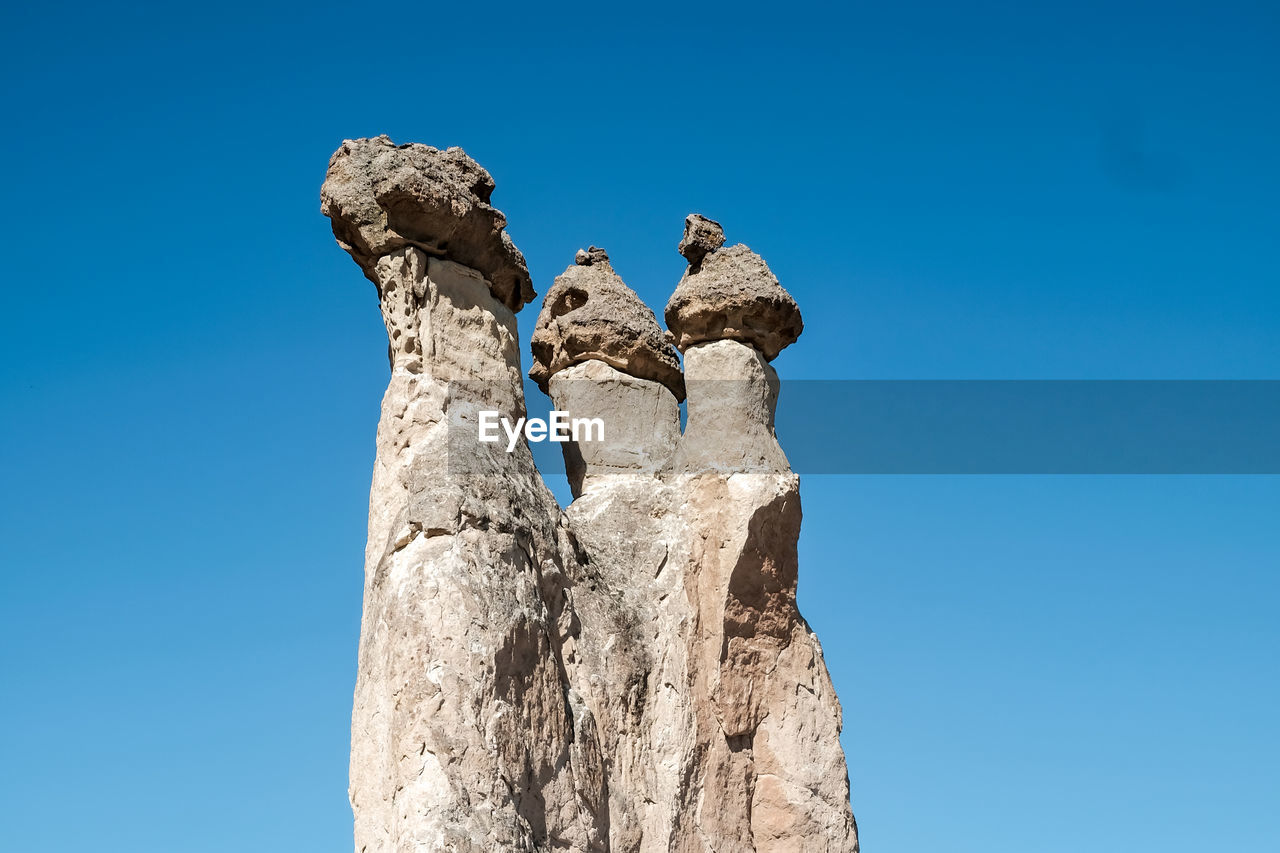 Low angle view of rock formation against clear blue sky