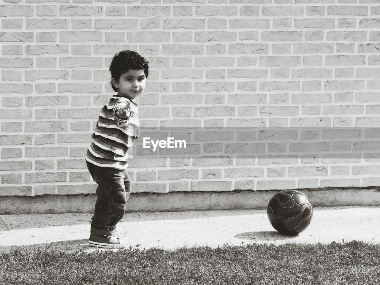 Side view portrait of boy gesturing while standing by soccer ball
