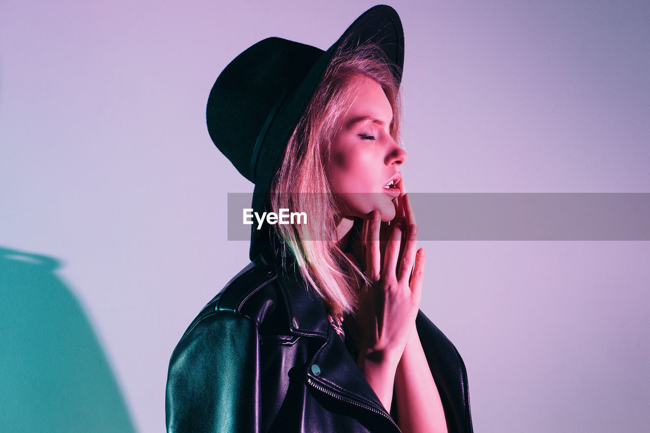 PORTRAIT OF BEAUTIFUL YOUNG WOMAN WEARING HAT AGAINST WALL