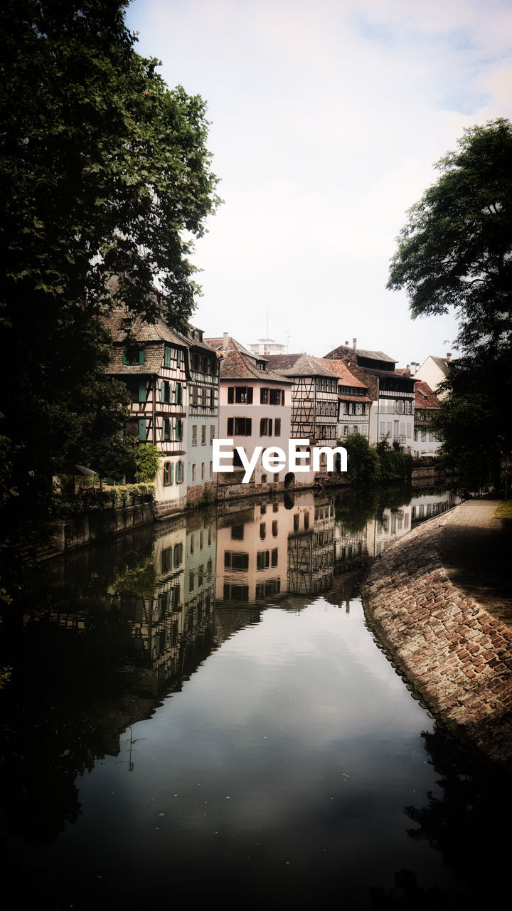 Buildings by lake against sky