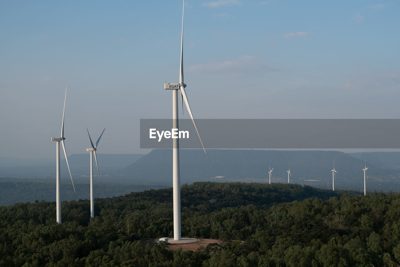 WINDMILLS ON LAND AGAINST SKY