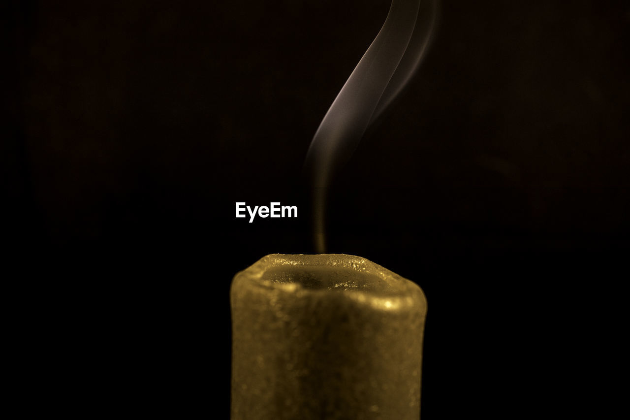 Close-up of burning candle against black background