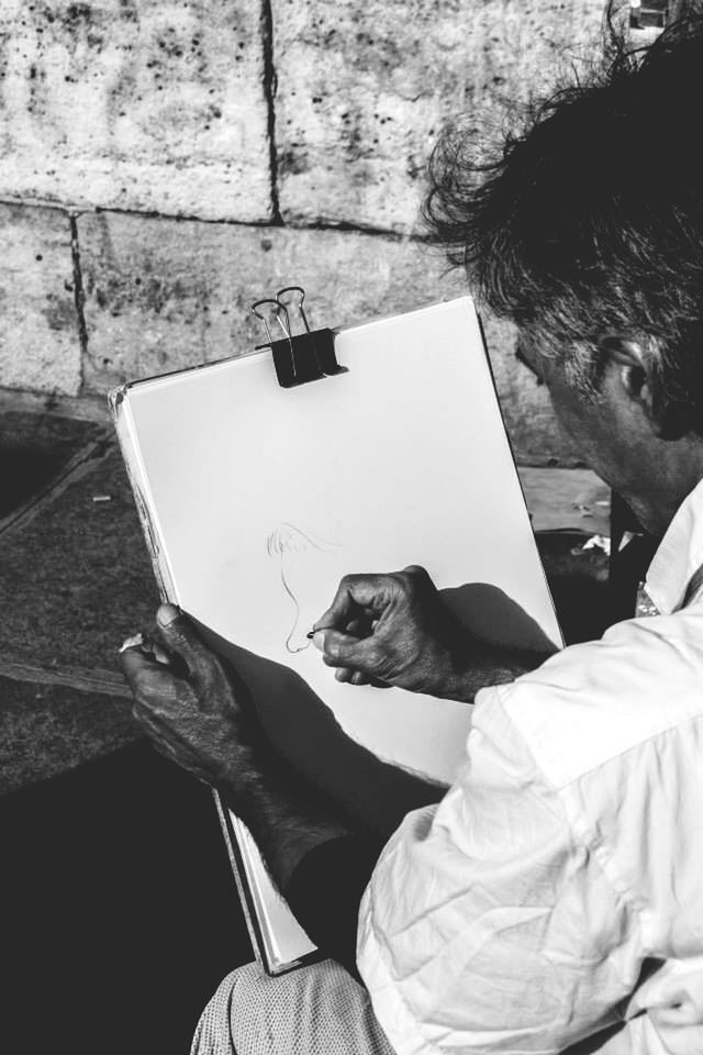 Cropped image of man drawing on paper against wall