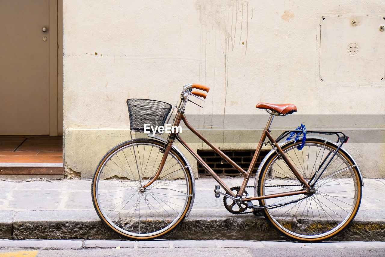 Bicycle on sidewalk against wall