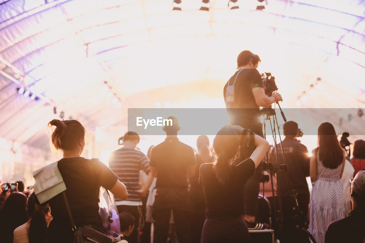 Rear view of people photographing at concert hall