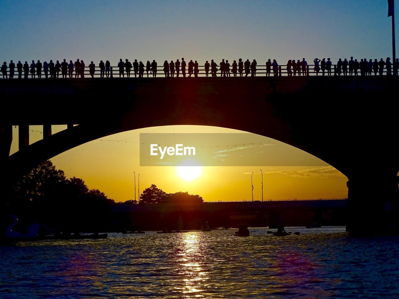 Silhouette bridge over river against sky during sunset