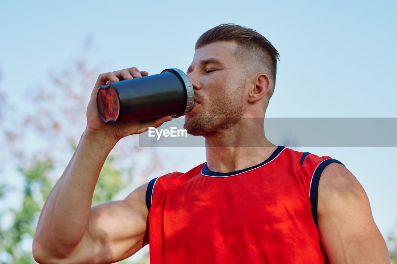 close-up of woman drinking water from bottle against sky