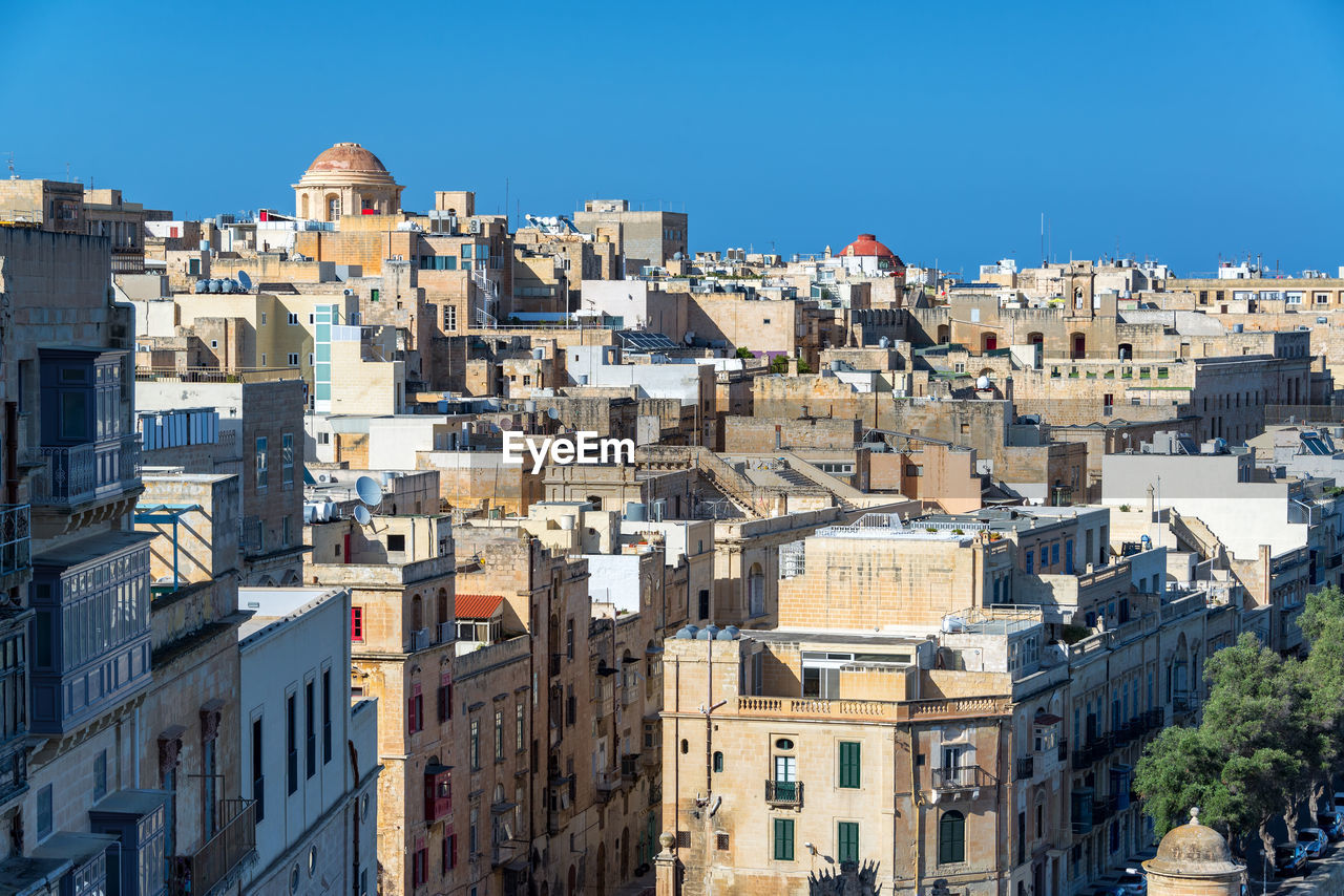 Buildings in city against clear blue sky