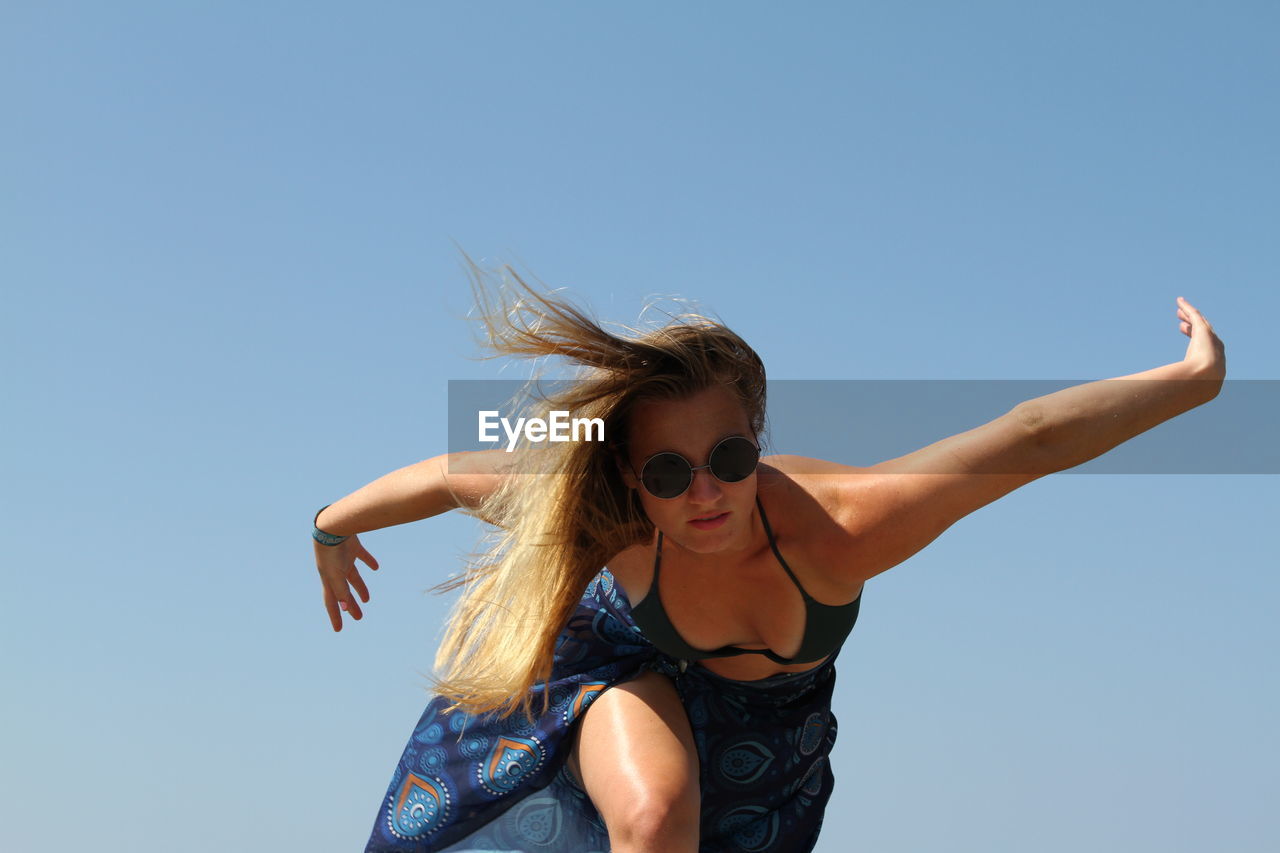 Young woman standing at beach against clear sky