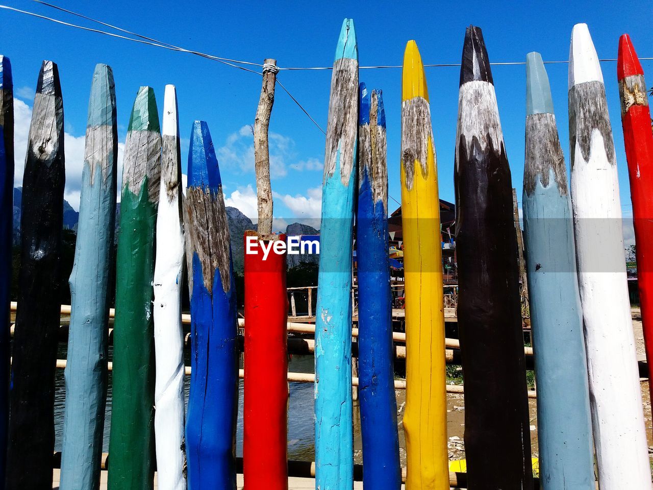 Close-up of multi colored wooden posts against lake