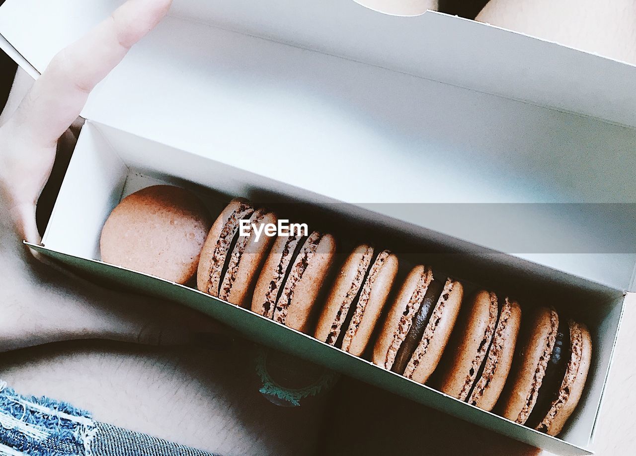 Midsection of person holding box with macaroons