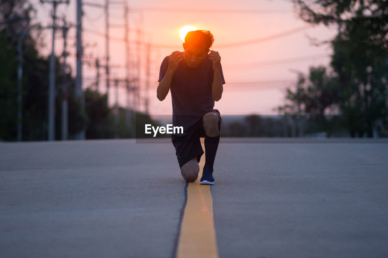 Man running on road at sunset