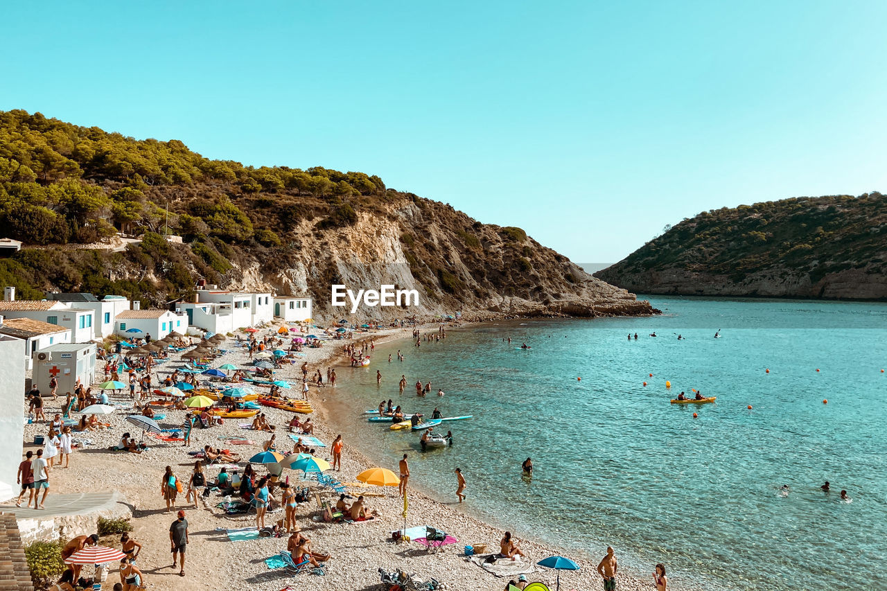 PEOPLE AT BEACH AGAINST CLEAR SKY