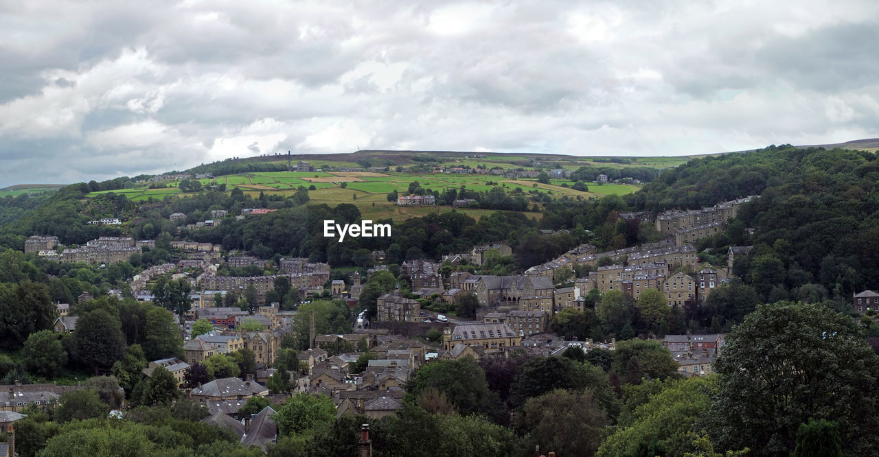Wide panoramic view of the town of hebden bridge with streets surrounded by trees and pennine fields