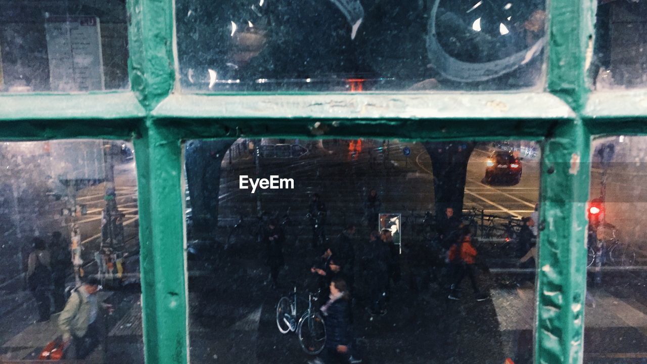 High angle view of people on street seen through glass window