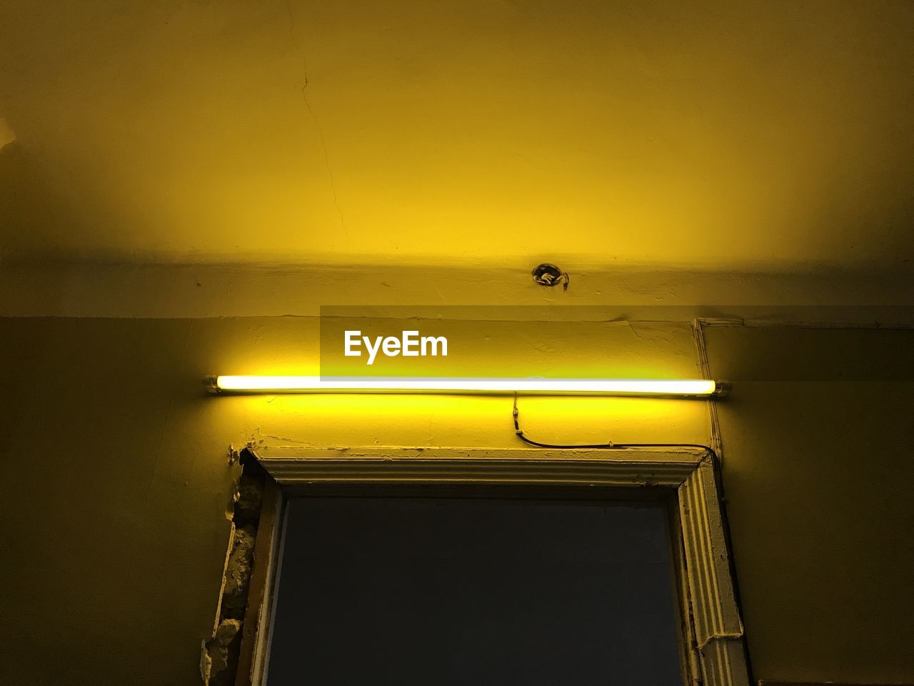 LOW ANGLE VIEW OF ILLUMINATED LAMP AGAINST WALL