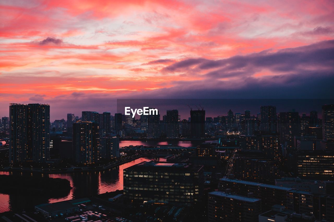 Illuminated cityscape against sky during sunset