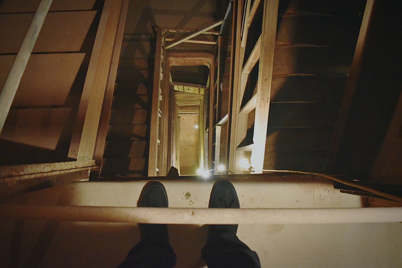 Low section of man standing on spiral staircase at night