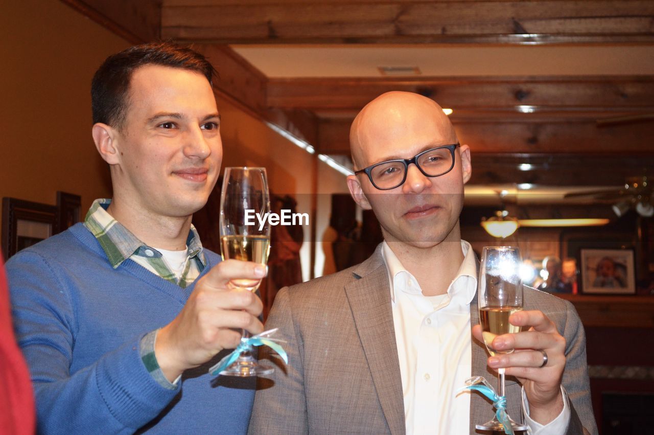 Male friends toasting champagne flutes in restaurant