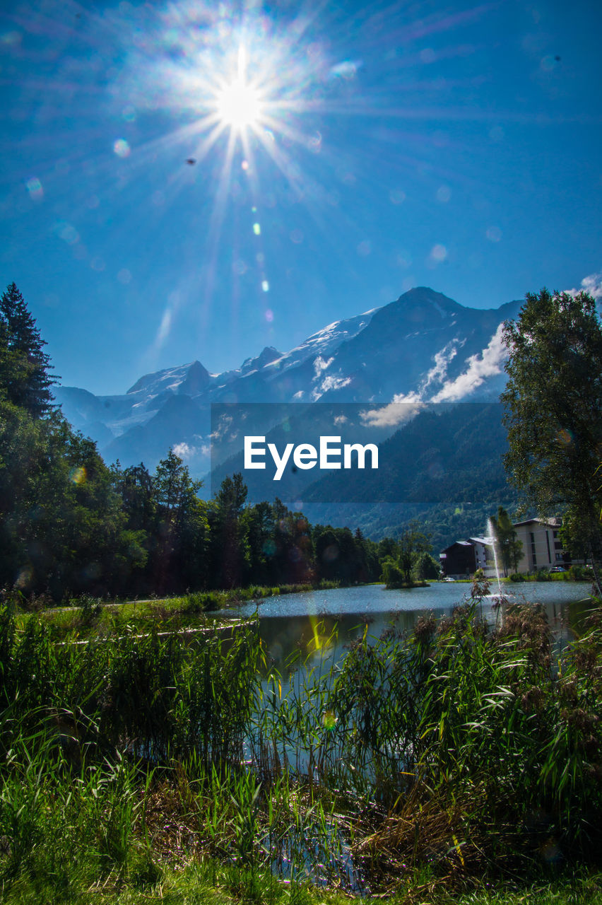 SCENIC VIEW OF LAKE BY MOUNTAINS AGAINST BRIGHT SKY