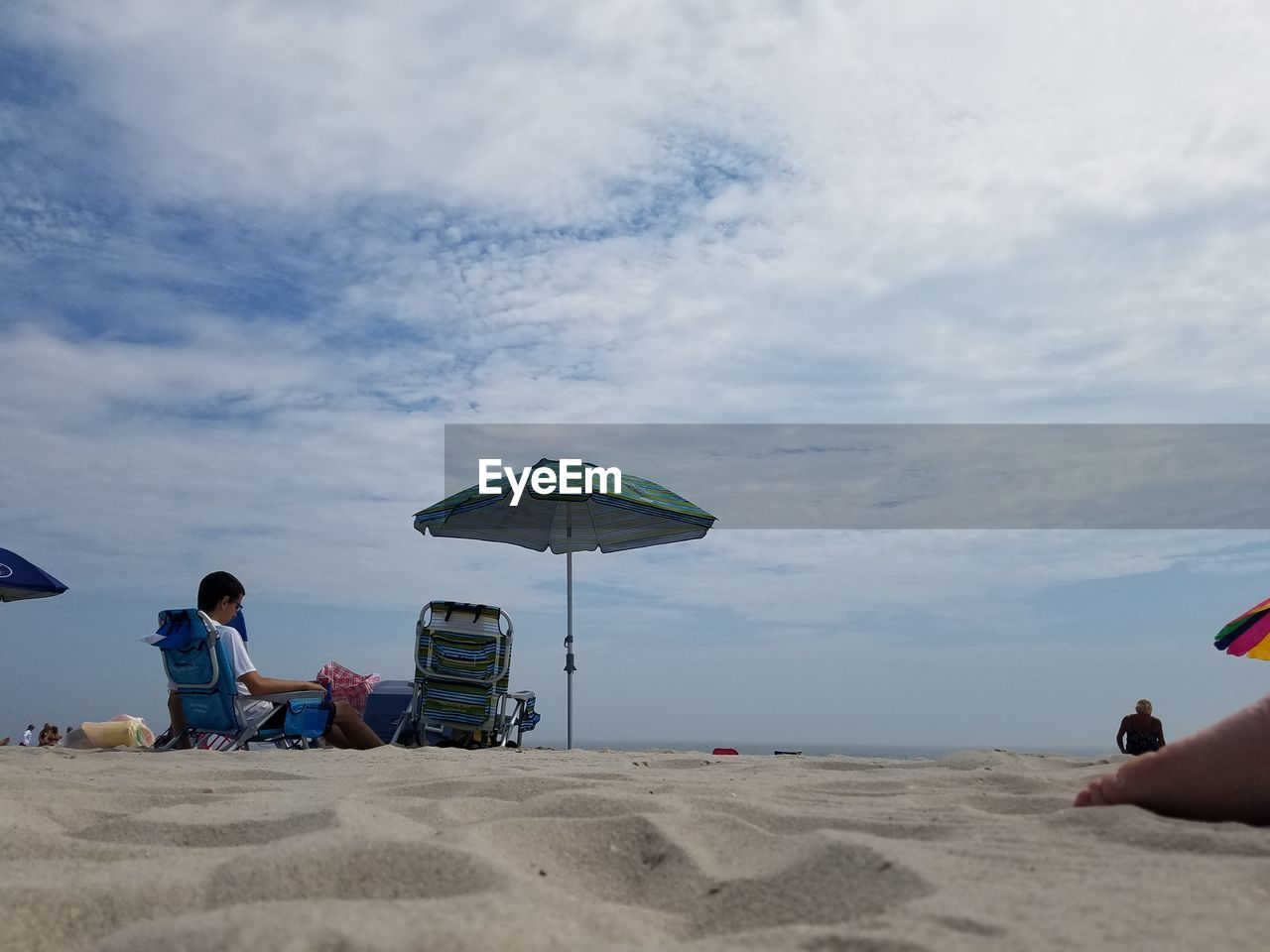 People sitting on chair at beach against sky