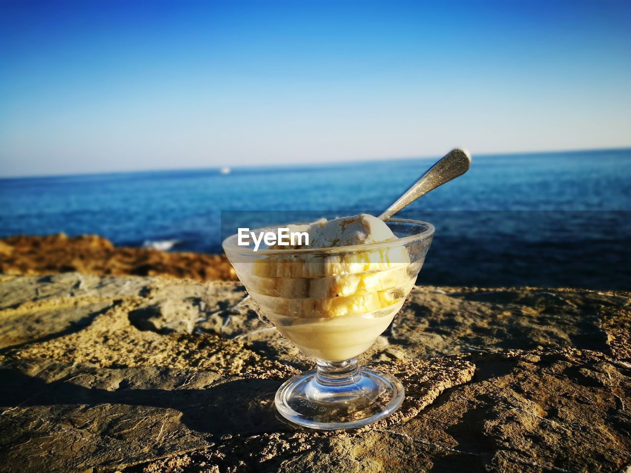 Close-up of drink by sea against clear sky