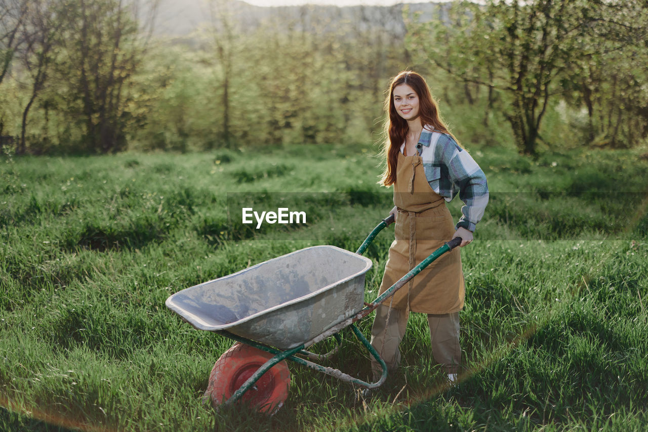 Portrait of young farmer with wheelbarrow in farm