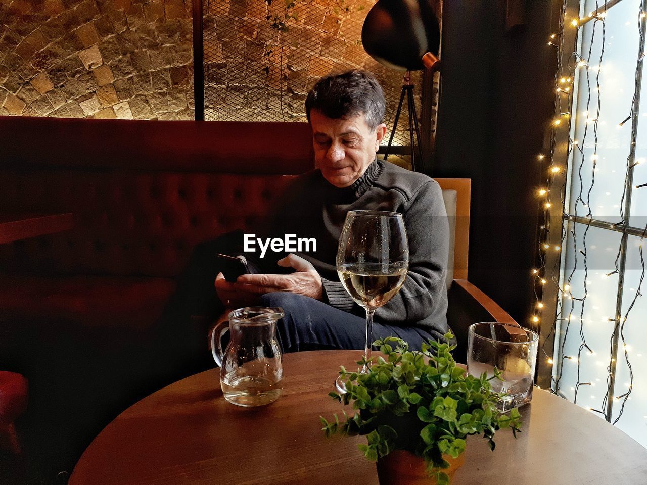 Man using phone while sitting by table at restaurant