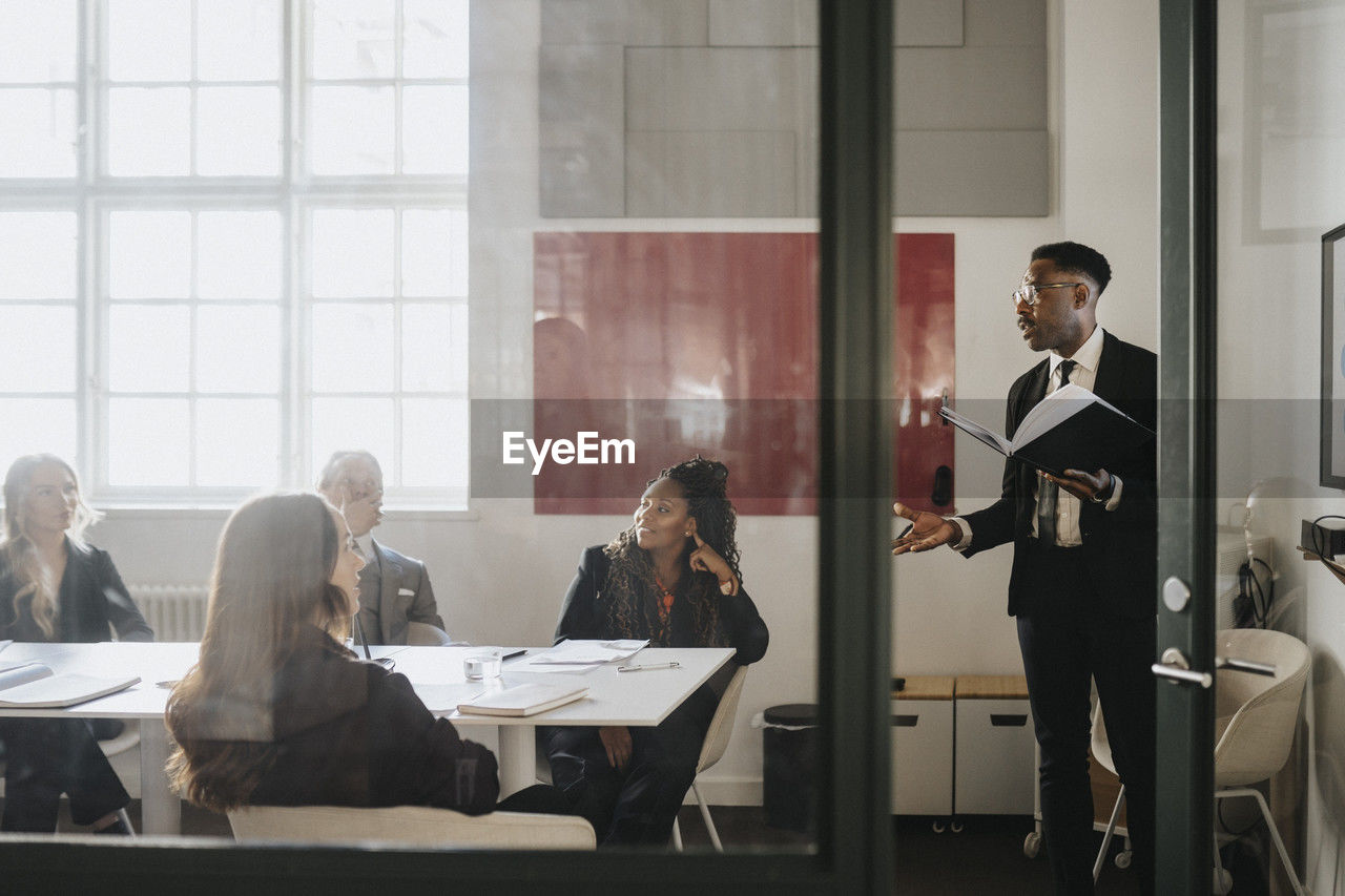 Mature businessman explaining male and female colleagues during meeting in board room at office