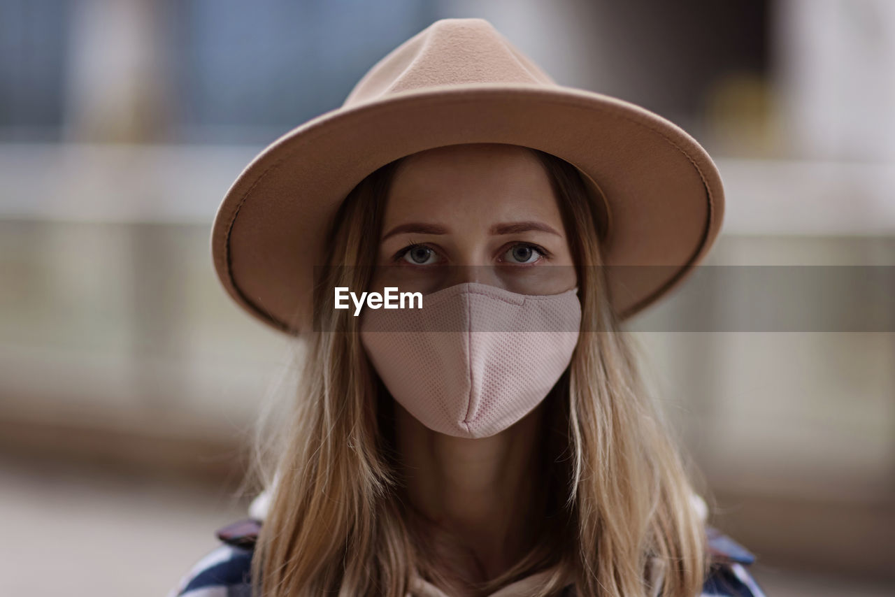 Portrait of young woman wearing hat and mask outdoors