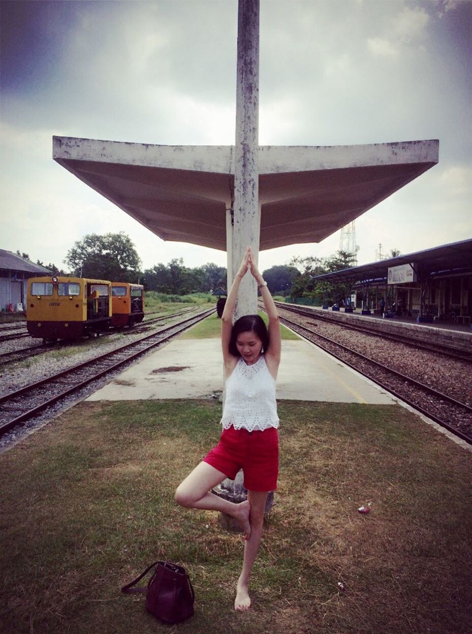 Young woman meditating while standing at railroad platform