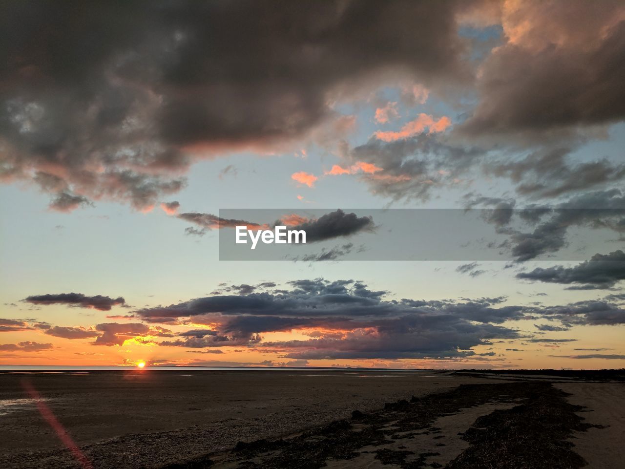 SCENIC VIEW OF BEACH AGAINST DRAMATIC SKY