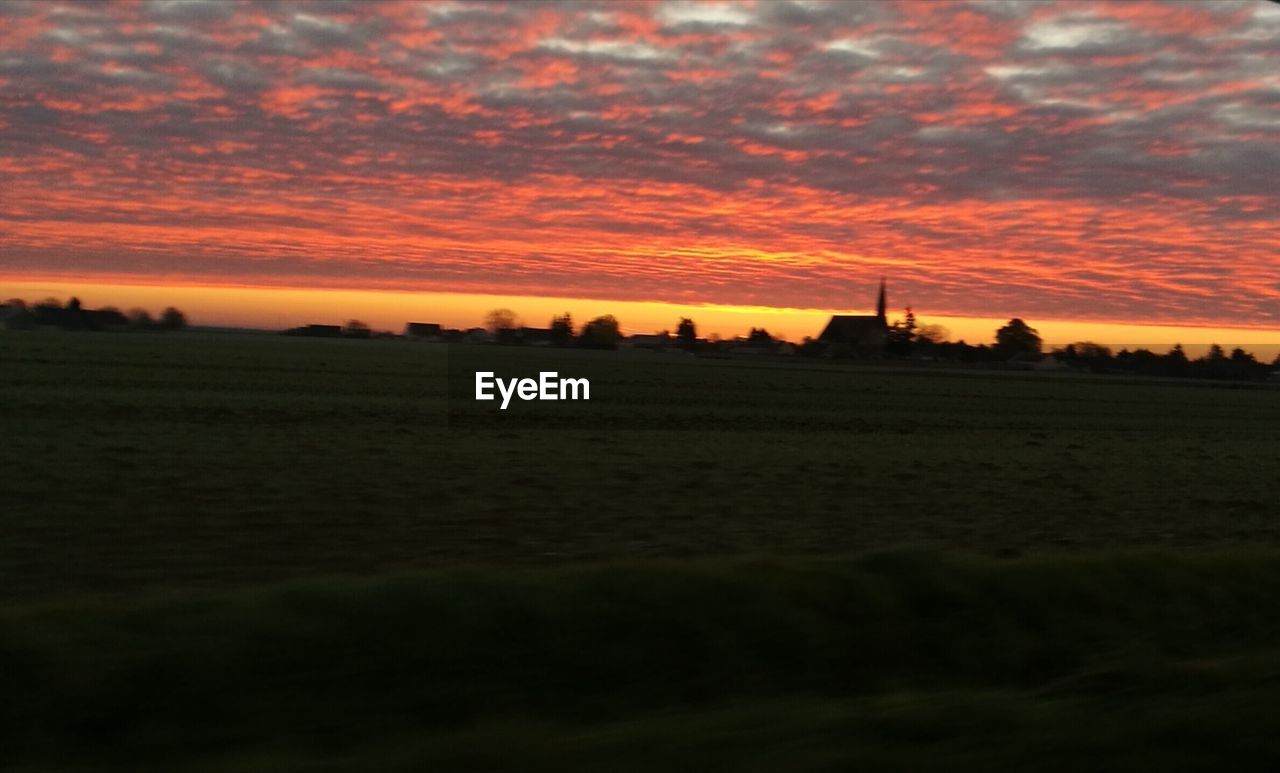 SILHOUETTE FIELD AGAINST ORANGE SKY