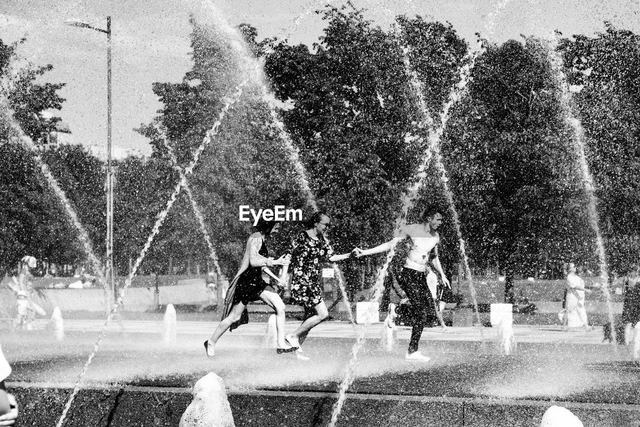 PEOPLE PLAYING WITH FOUNTAIN IN WATER