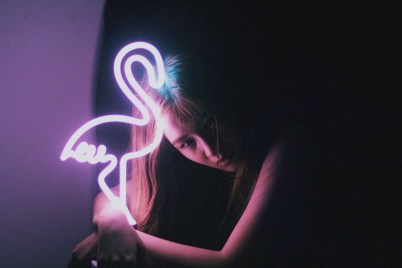 Young woman with neon flamingo sign