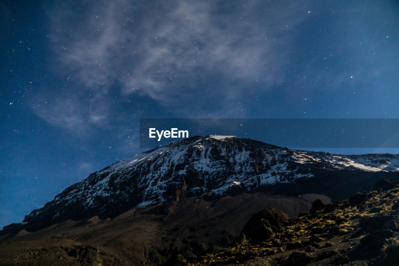 Scenic view of snowcapped mountains against sky at night