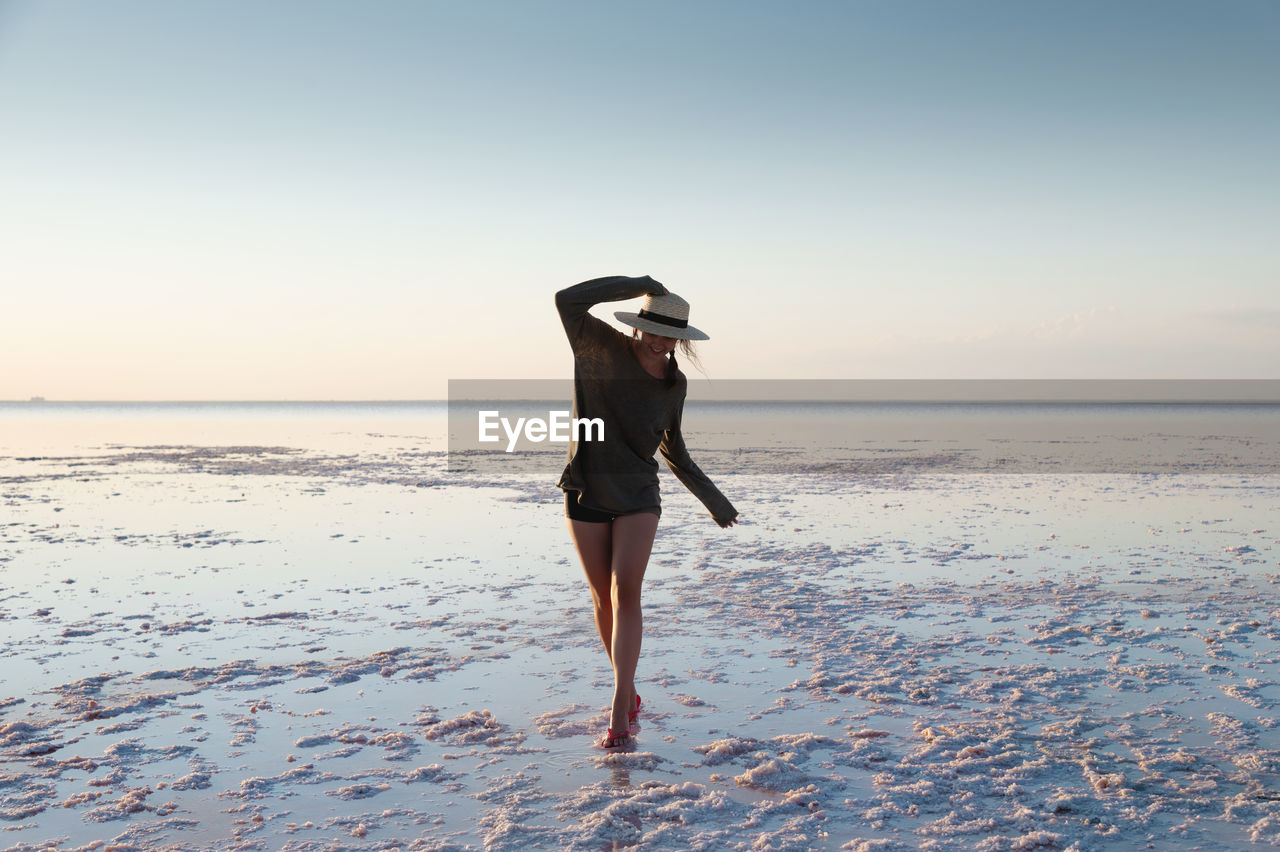 Charming romantic woman serenely walks through the colorful landscape of salt marshes on a pink lake