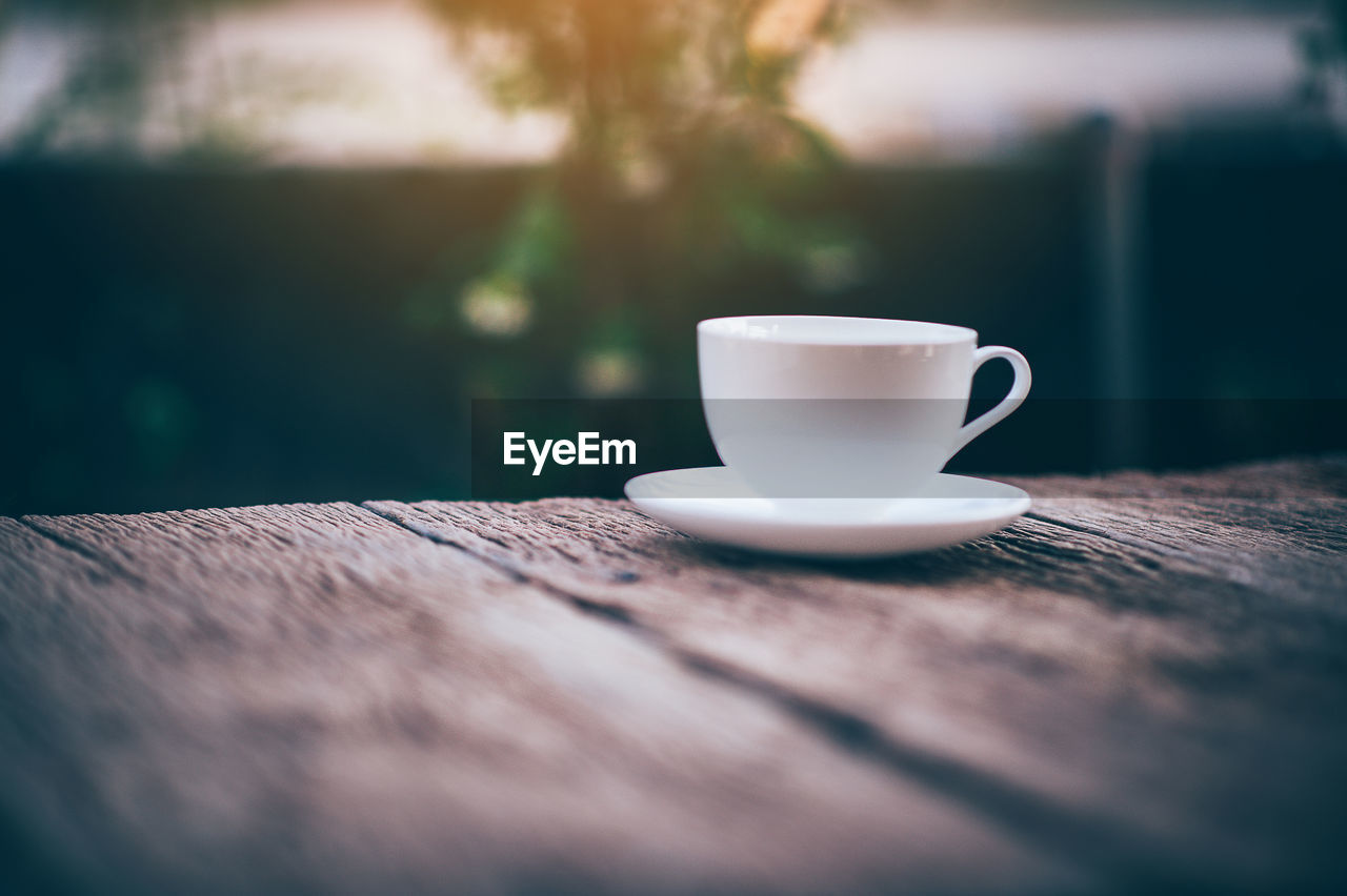 CLOSE-UP OF COFFEE CUP ON TABLE AGAINST BLURRED BACKGROUND