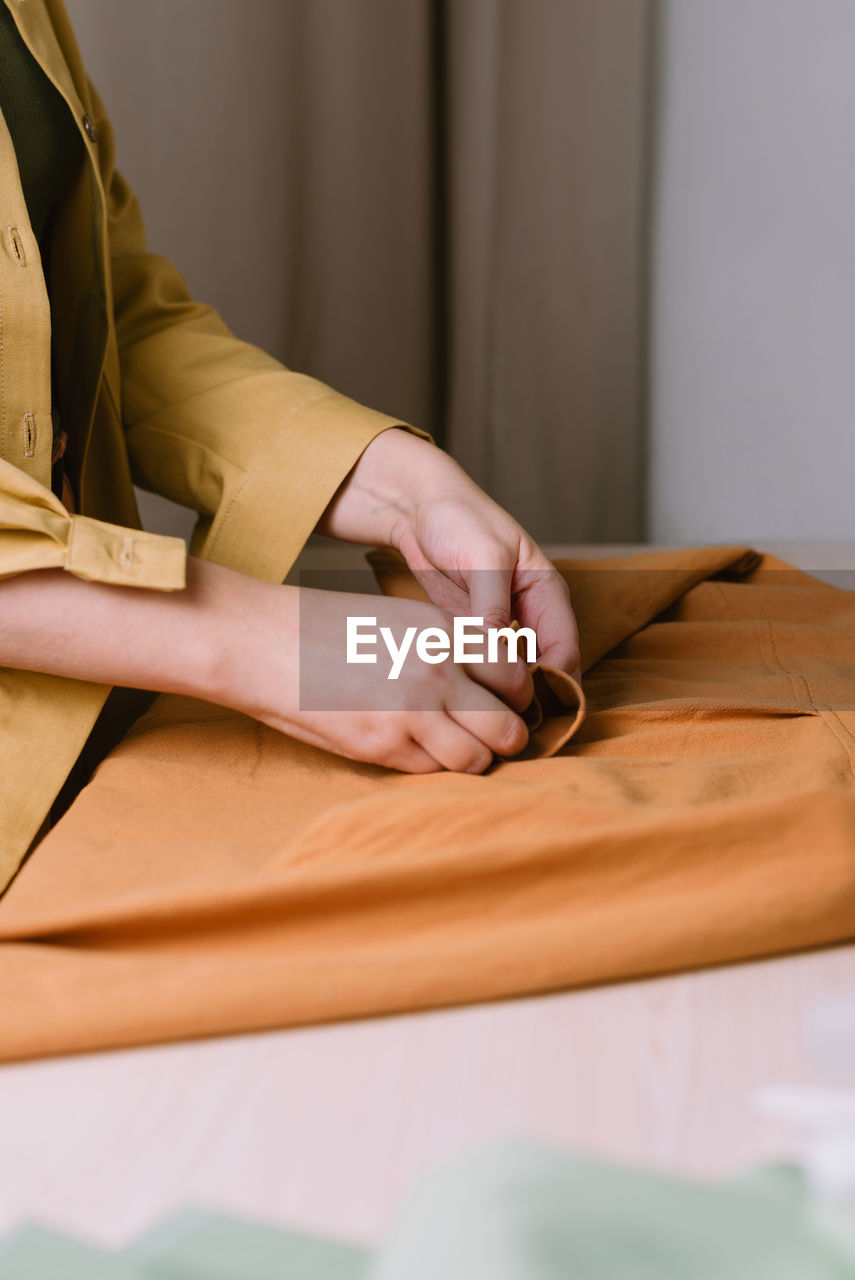 Midsection of woman sitting on table at home