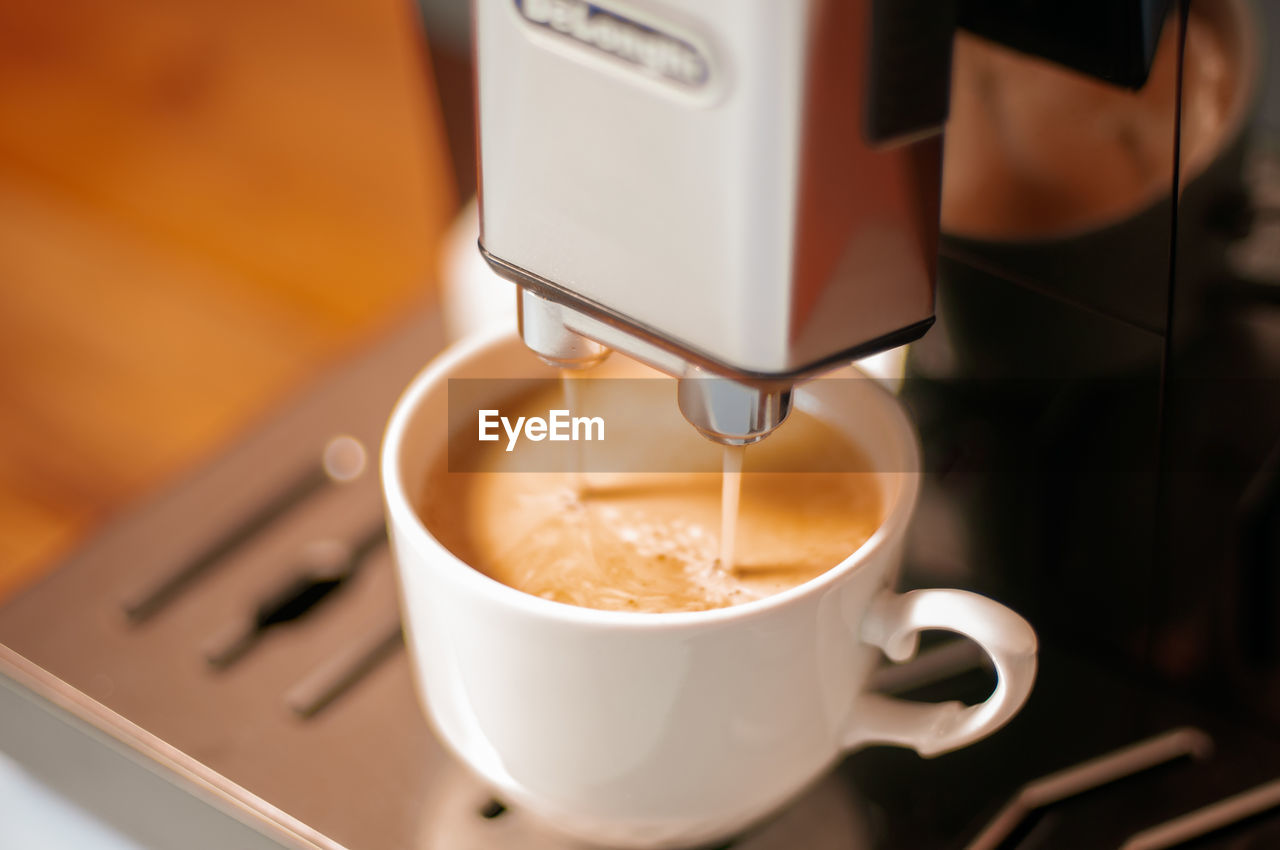 Modern coffee machine with a partially full cup of coffee on table in kitchen