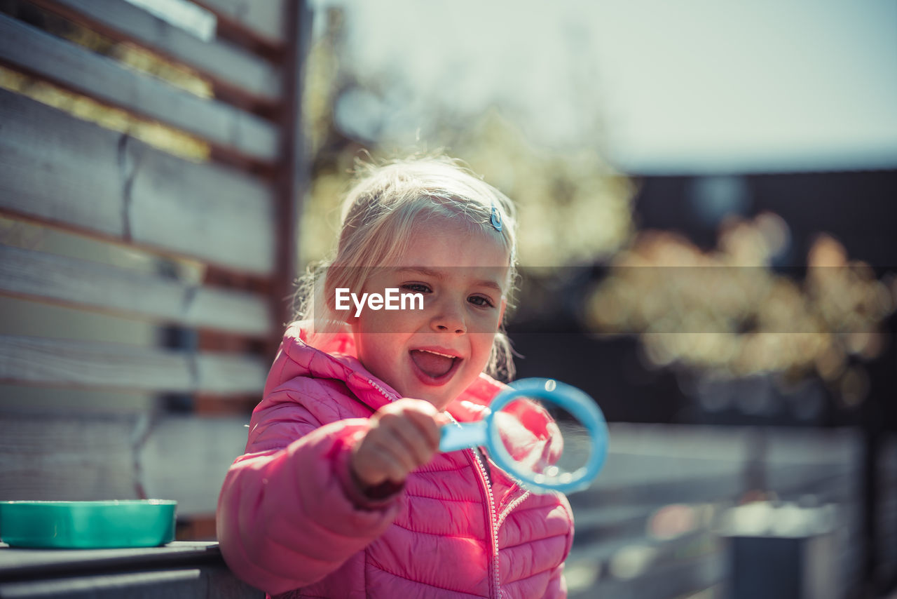 Girl blowing bubbles while standing at park