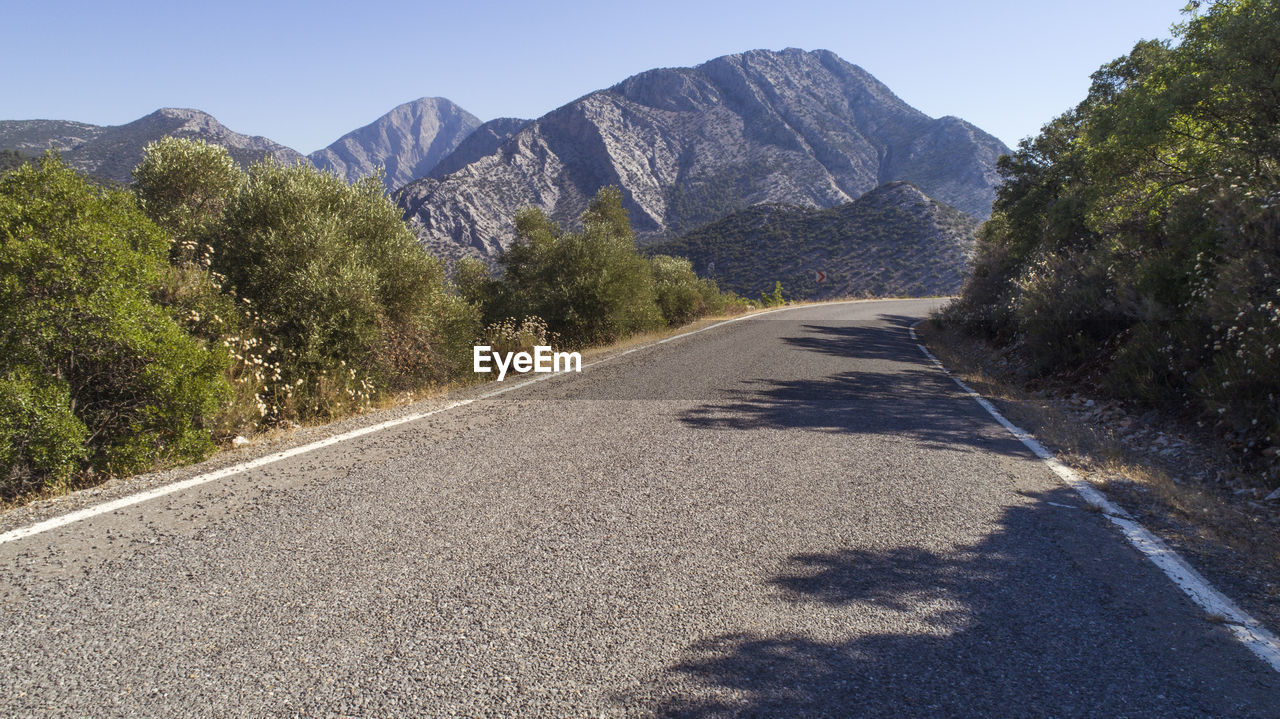 Road amidst trees and mountains against sky