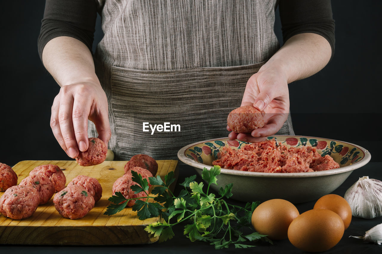 Female chef shapes minced meat to make homemade meatballs