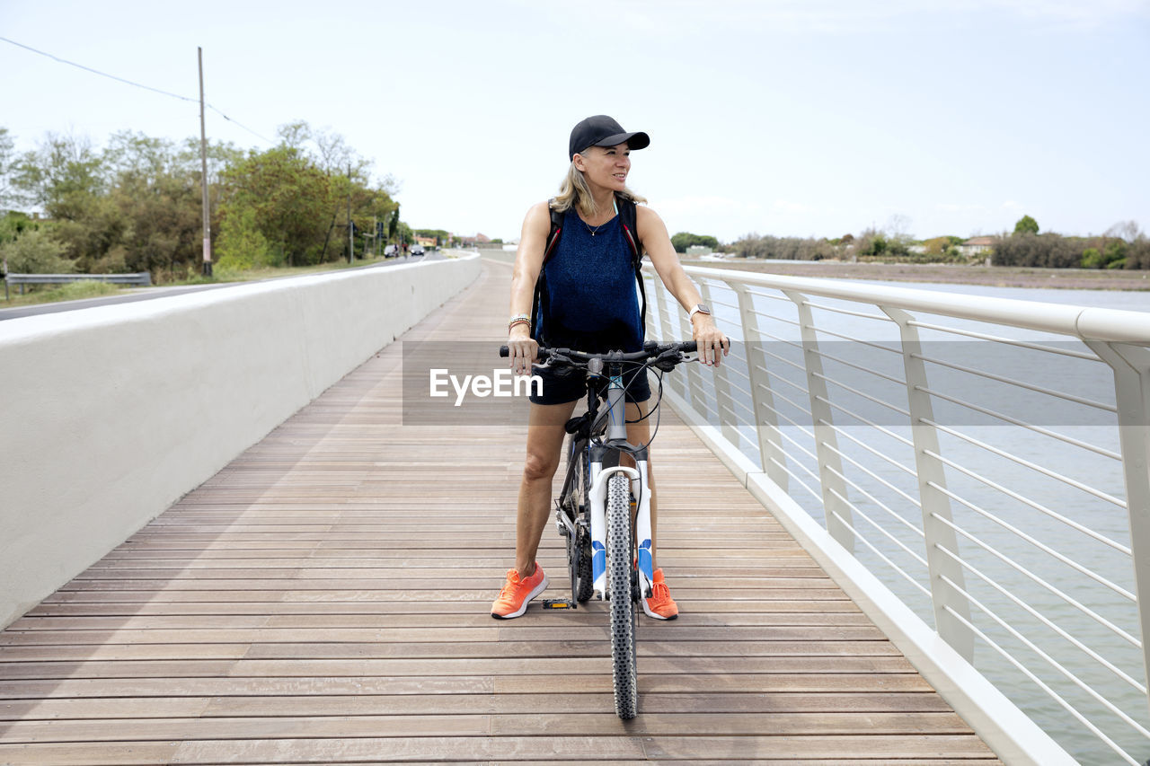 Active senior woman riding bicycle on promenade